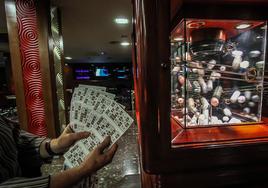 Una empleada muestra varios cartones en una sala de bingo antes de comenzar el juego
