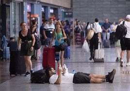 Un viajero intenta descansar ante la demora de los trenes.