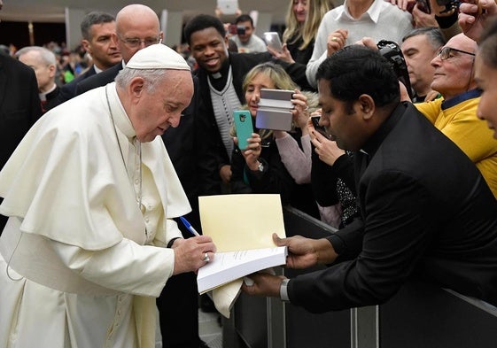El papa Francisco firma un libro a un feligrés en 2019.