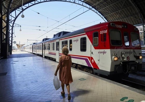 Una pasajera junto a un tren de Renfe.