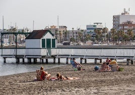 Varias personas toman el sol junto al balneario de Las Monjas, en la playa de Villananitos de San Pedro del Pinatar.